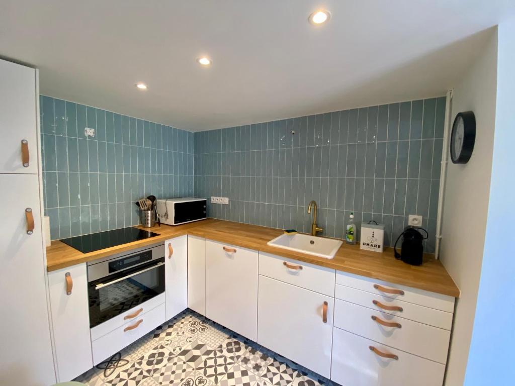 a kitchen with white cabinets and green tiles at La Petite Ardoise - Maison au calme pour 4 pers in Honfleur