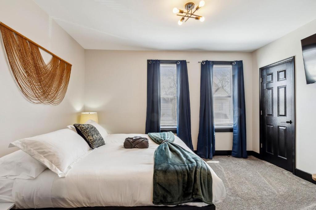 een slaapkamer met een groot wit bed en blauwe gordijnen bij Fairfax Urban Oasis - New Reno - 5 mins to Clinic in Cleveland