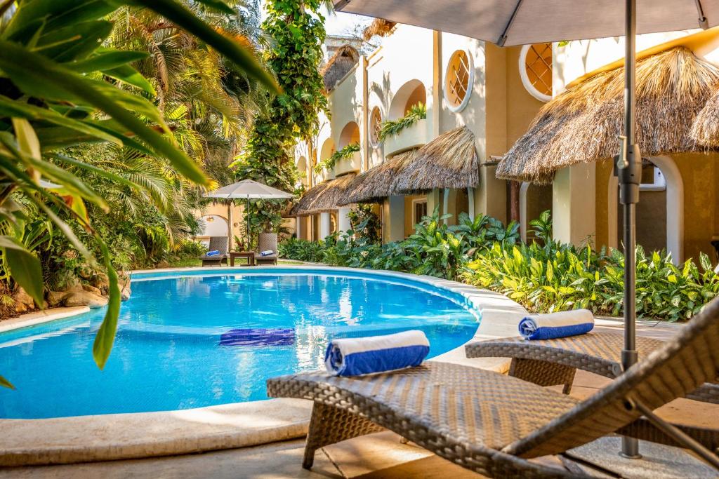 a swimming pool with two chairs and an umbrella at Hotel Villas Sayulita in Sayulita