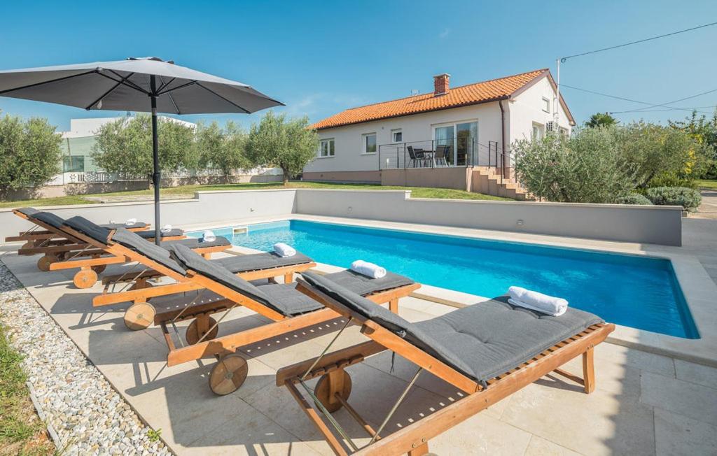 a swimming pool with lounge chairs and an umbrella at Villa Viktoria poll&garden view in Kaštelir