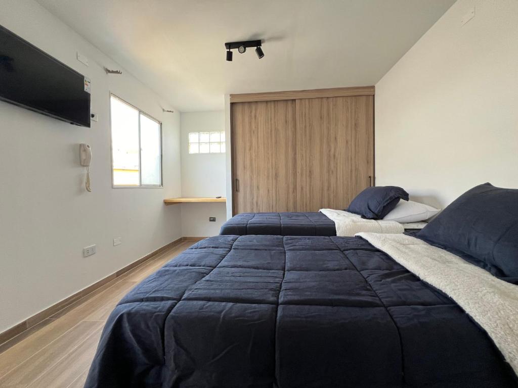 1 dormitorio con 2 camas y TV en la pared en AH alojamientos en Antofagasta