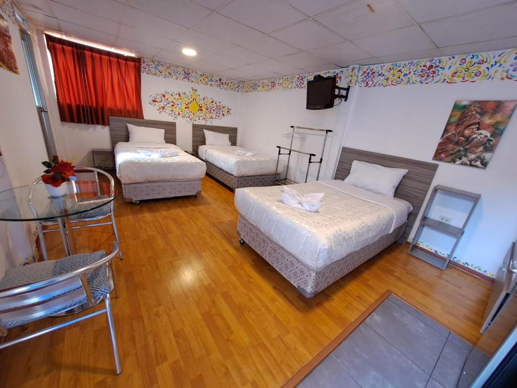 クスコにあるCUSCO DEPARTAMENTOSのベッド2台、テーブル、テレビが備わる客室です。