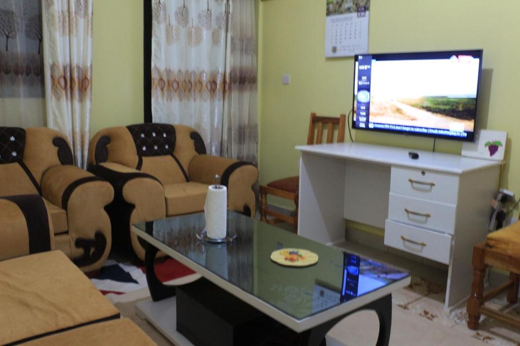 - un salon avec une télévision et une table dans l'établissement Chaka Furnished Apartments, à Kiganjo
