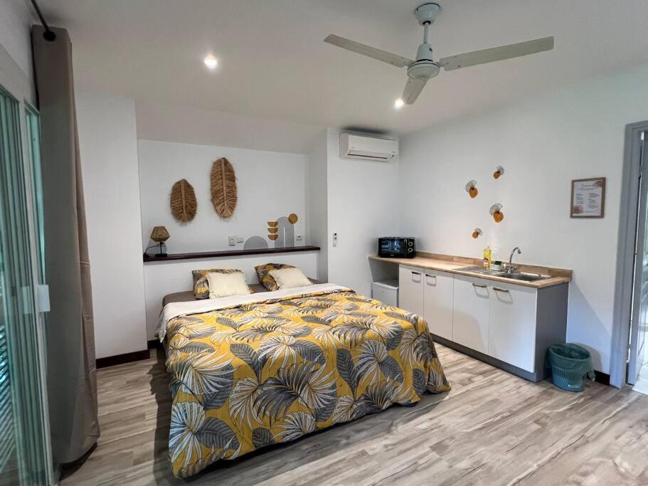 a bedroom with a bed and a kitchen with a sink at Bungalow Natura - Sarramea in Sarraméa