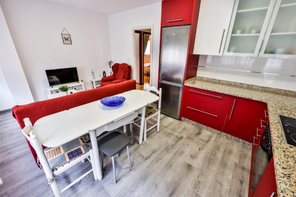 - une cuisine avec des placards rouges et une table dans une pièce dans l'établissement casa de Antonio, à Camariñas