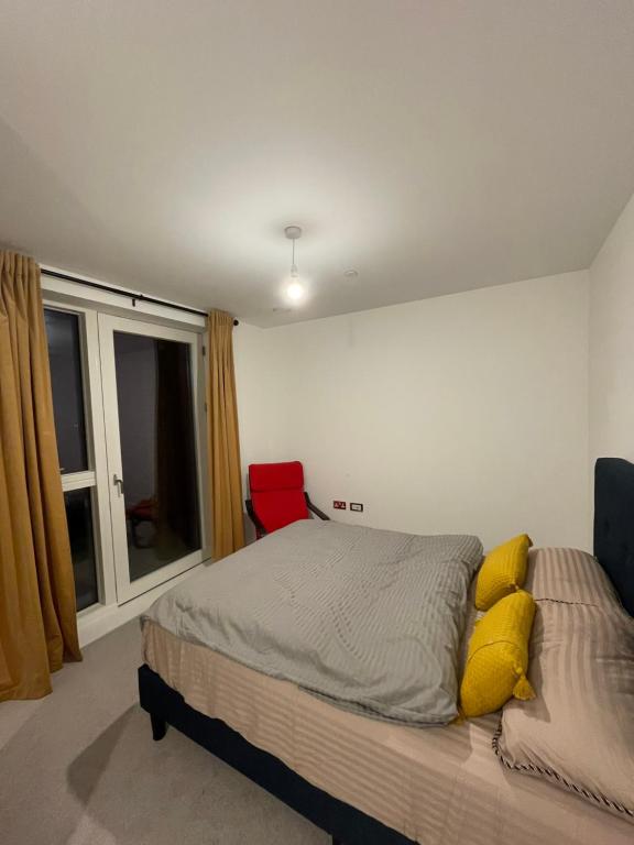 een slaapkamer met een bed met gele kussens en een raam bij The Velvet Vista in Croydon