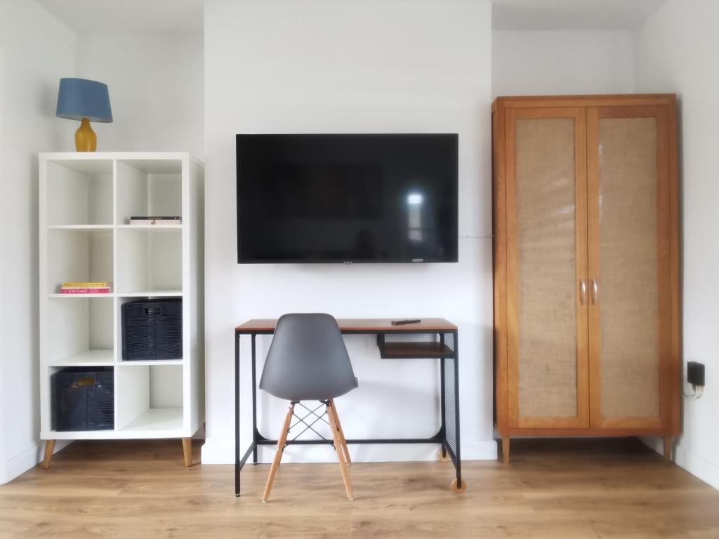 einen Schreibtisch mit Stuhl und einen TV an der Wand in der Unterkunft Contemporary 3 bedroom house in Nottingham