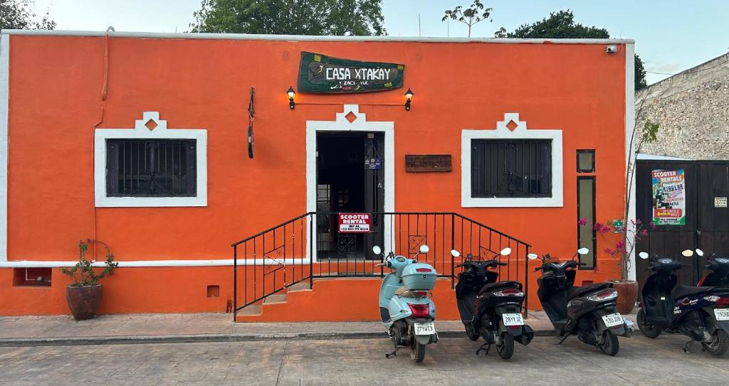 Un bâtiment orange avec des scooters garés devant. dans l'établissement Hostel Casa Xtakay, à Valladolid