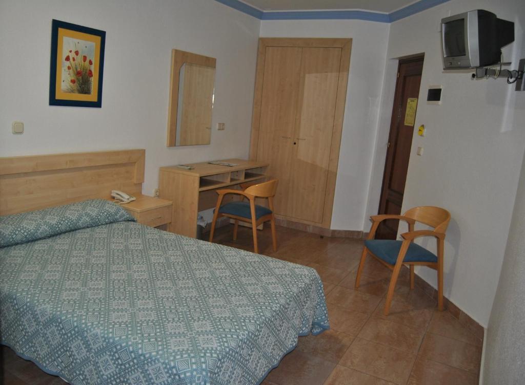 1 dormitorio con 1 cama, mesa y sillas en Hostal Blumen, en Algeciras