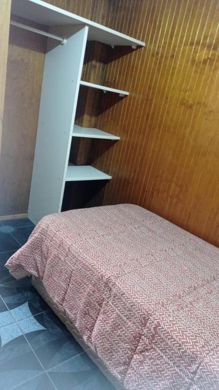 ein Schlafzimmer mit einem Bett und einer Holzwand in der Unterkunft Departamento Interior Pablo Neruda in Temuco