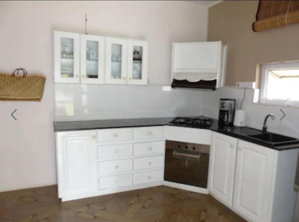 a kitchen with white cabinets and a black counter top at Beehive in Pamplemousses Village