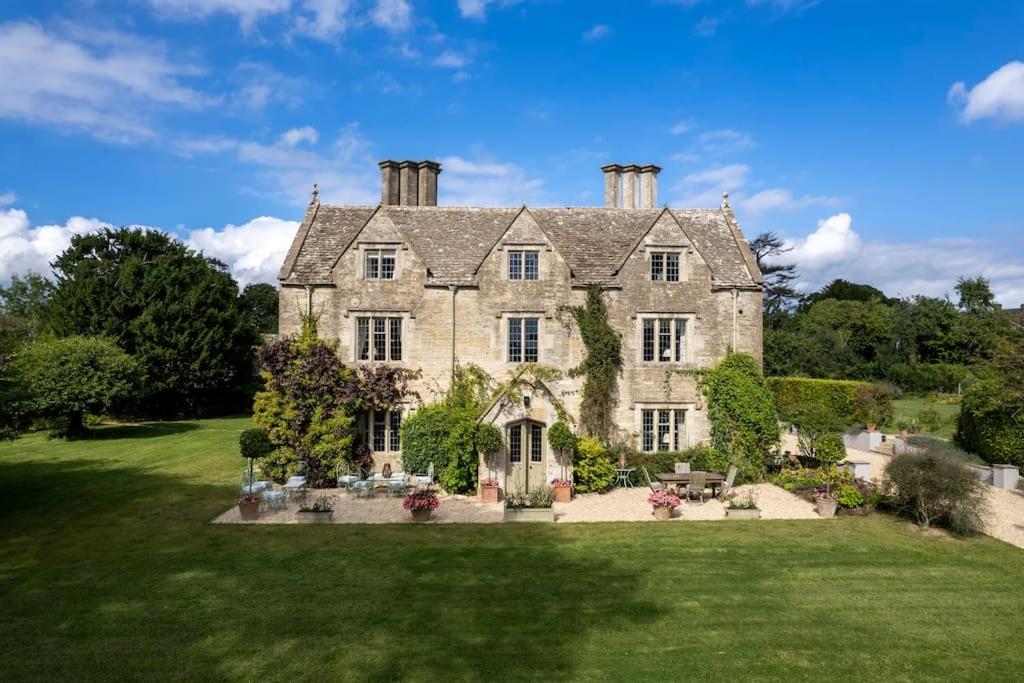 uma antiga casa de pedra com um grande quintal em 7 Bedrooms Manor Farmhouse with heated pool em Cirencester