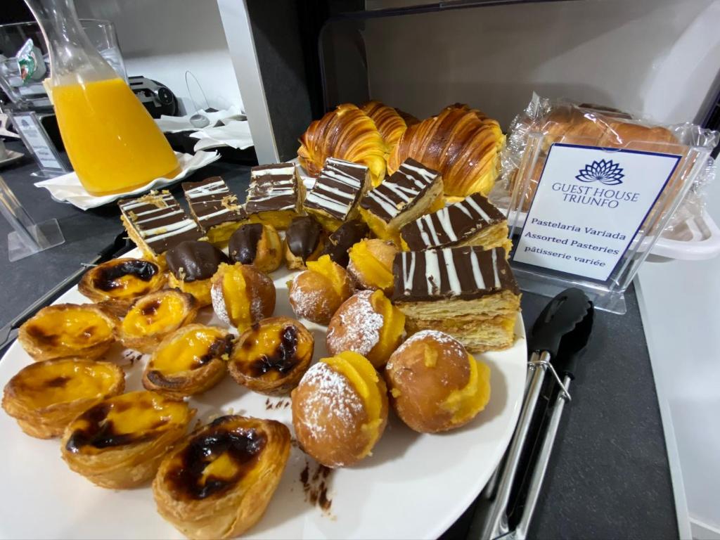 a plate of donuts and other pastries on a counter at Guest House Triunfo in Porto