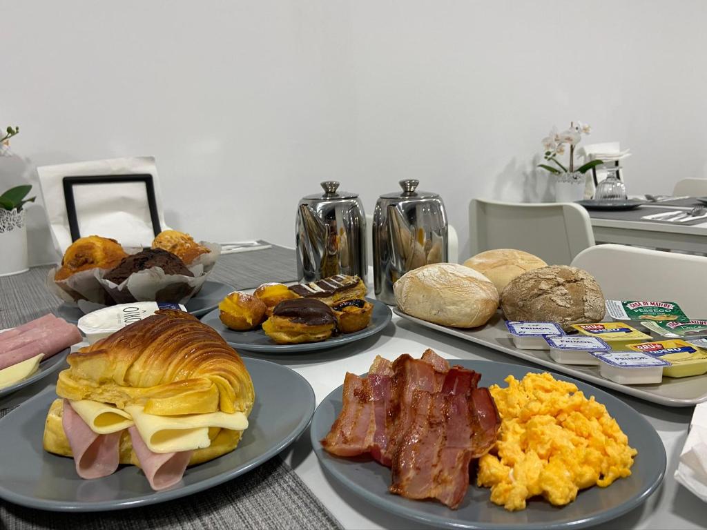a table with different types of breakfast foods on plates at Guest House Triunfo in Porto