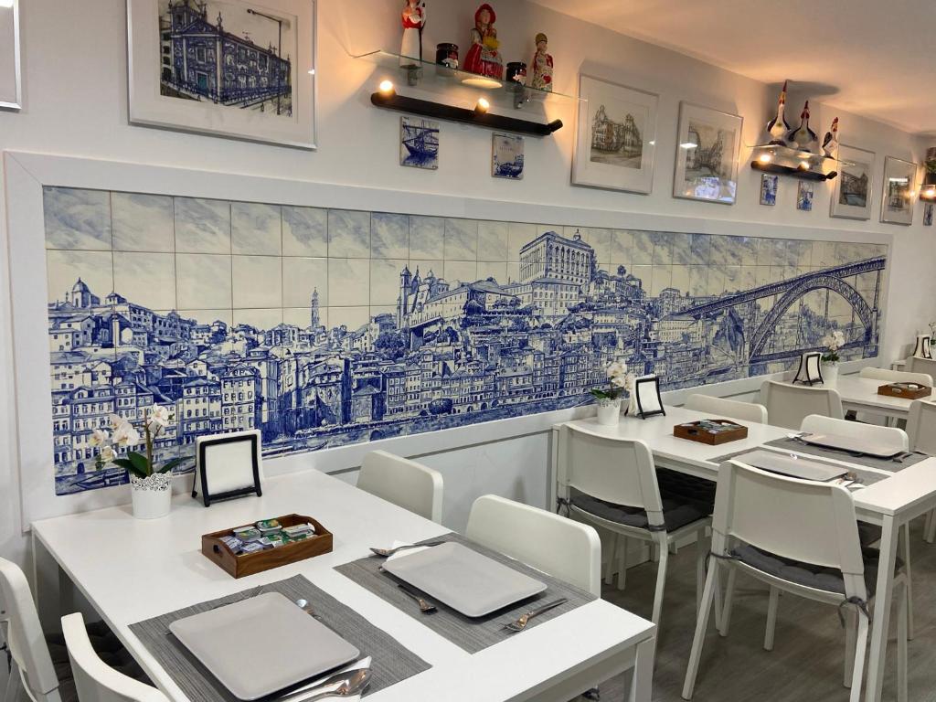a restaurant with white tables and a mural on the wall at Guest House Triunfo in Porto