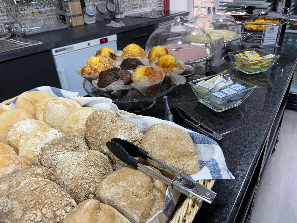 a bunch of breads and pastries on a counter at Guest House Triunfo in Porto
