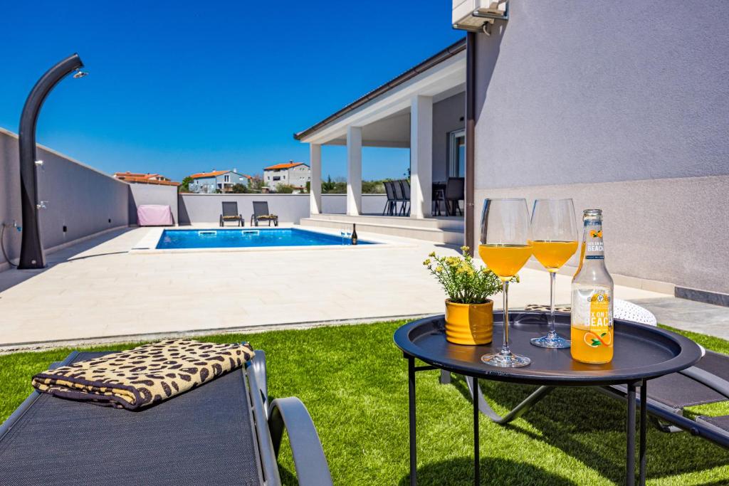 ein Tisch mit zwei Gläsern Wein auf einem Hof in der Unterkunft Serenity home Villa Tea with heated pyrolysis salt water in Loborika