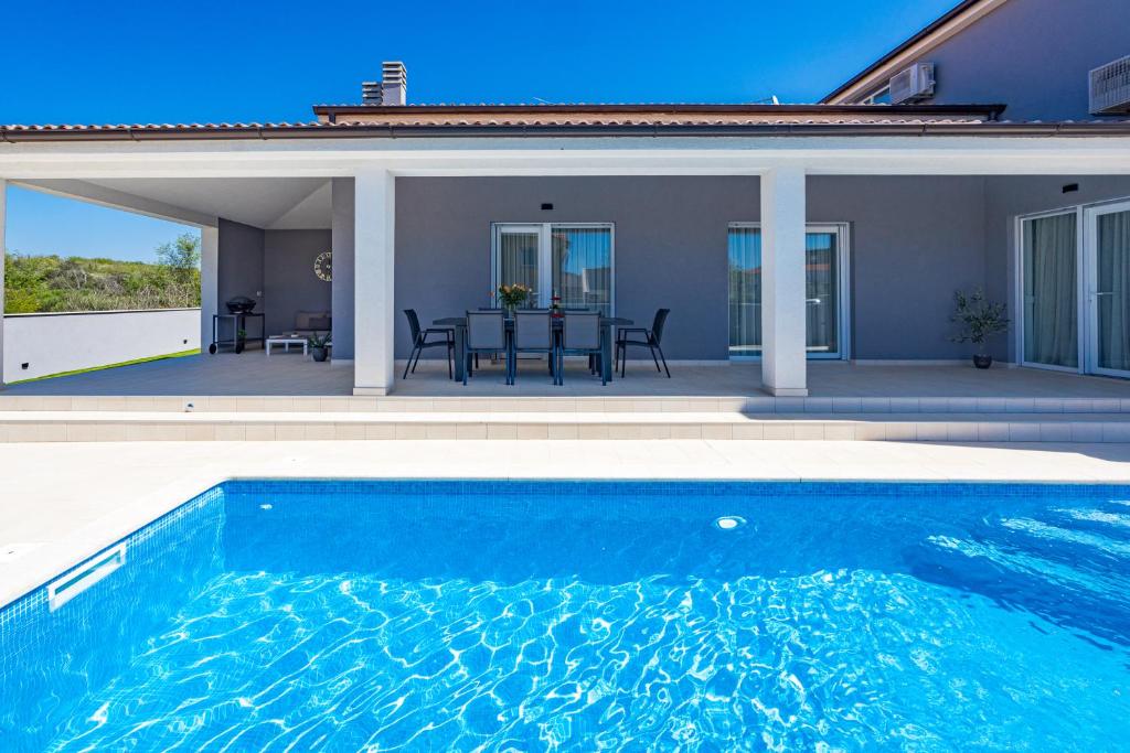 a swimming pool in front of a house at Villa Tea with heated pool in Loborika