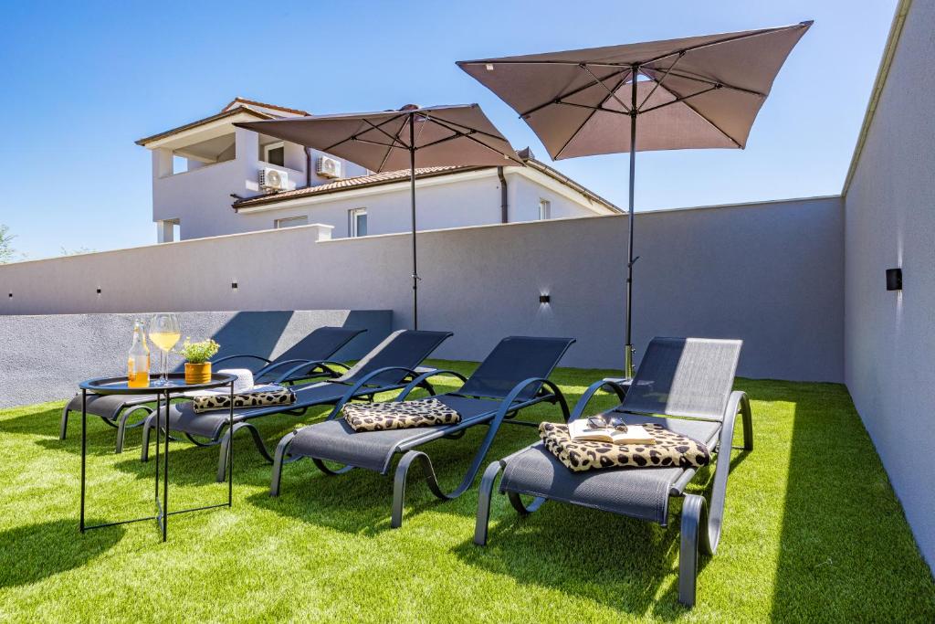 eine Gruppe Stühle und einen Tisch mit einem Sonnenschirm in der Unterkunft Serenity home Villa Tea with heated pyrolysis salt water in Loborika