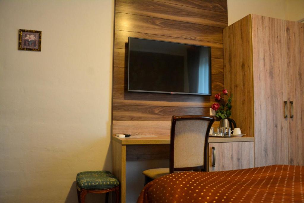 a bedroom with a desk and a television on a wall at Penzión Pulse in Podhájska