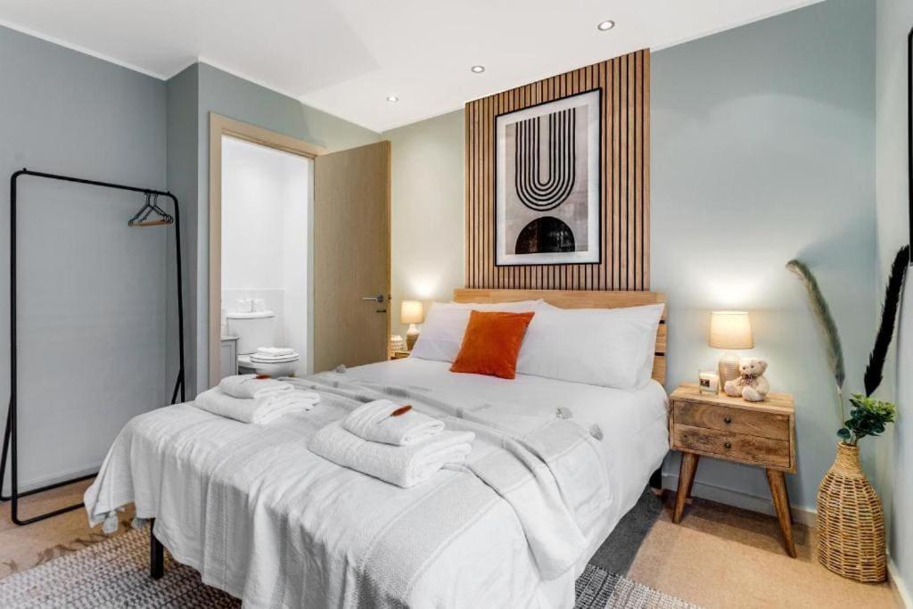 a bedroom with a large bed with white sheets and orange pillows at Walk to Marlowe Theatre from our lovely flat in the city centre in Canterbury