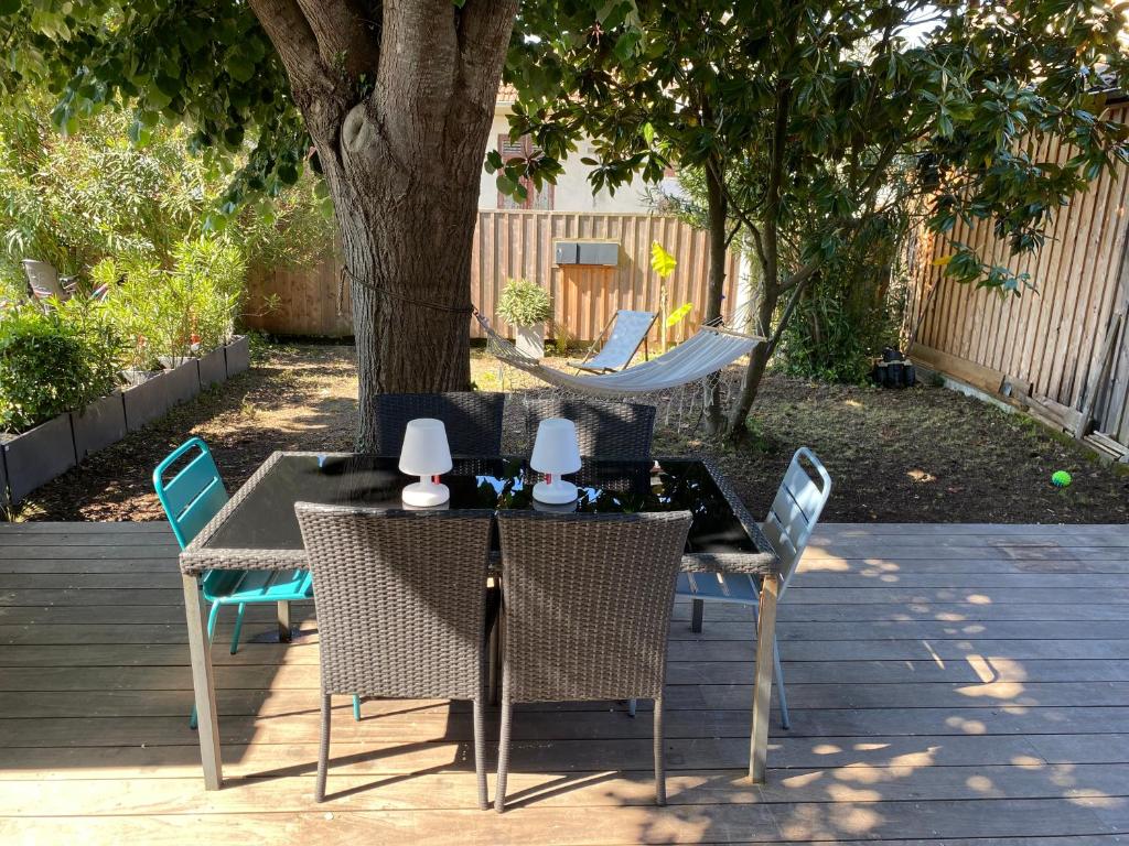 une table et des chaises sur une terrasse sous un arbre dans l'établissement Villa à 2 min à pied de la plage, à Arcachon