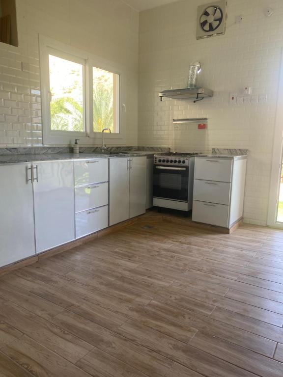 a kitchen with white cabinets and a wooden floor at إستراحة وادي بني خالد in Dawwah