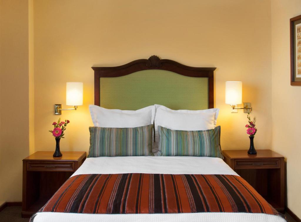 una camera da letto con un grande letto con cuscini e due lampade di Hotel Francia Aguascalientes a Aguascalientes