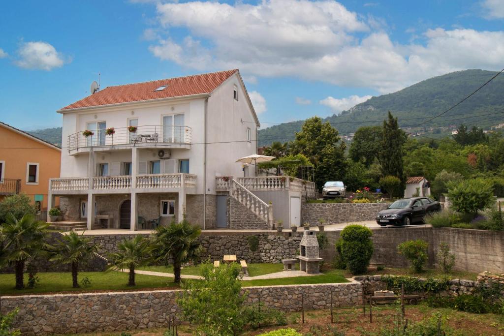 a large white house with a stone wall at Apartment Mladen in Ičići