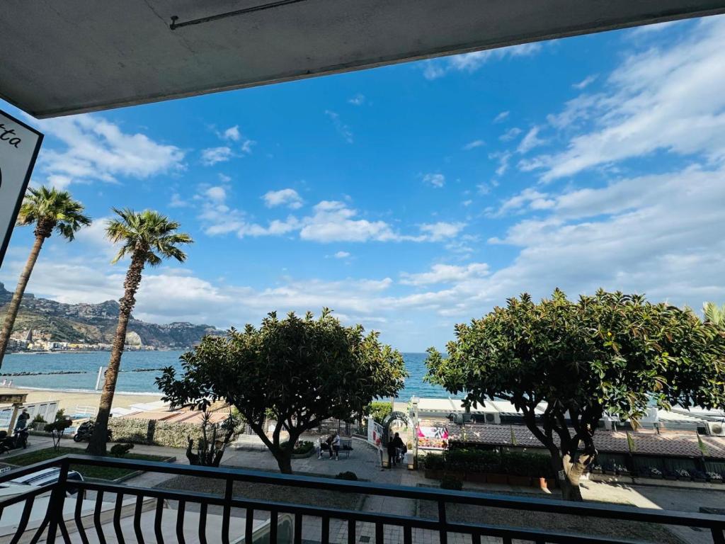 ジャルディーニ・ナクソスにあるCase Vacanze di Isabella Stoiaのバルコニーからビーチとヤシの木の景色を望めます。
