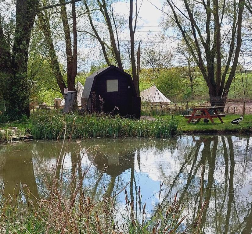 uma tenda e uma mesa de piquenique ao lado de um lago em Rum Bridge Fisheries "The Cabin" em Clare