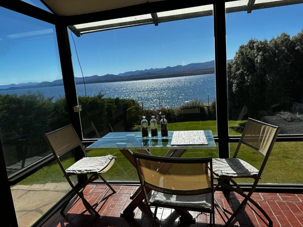 a table and chairs on a patio with a view of the water at Casa de las Chacras 2 in San Carlos de Bariloche