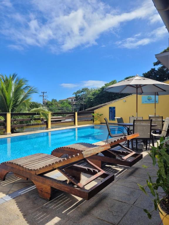 a pool with a picnic table and an umbrella at Meu Cantinho Familiar in Búzios