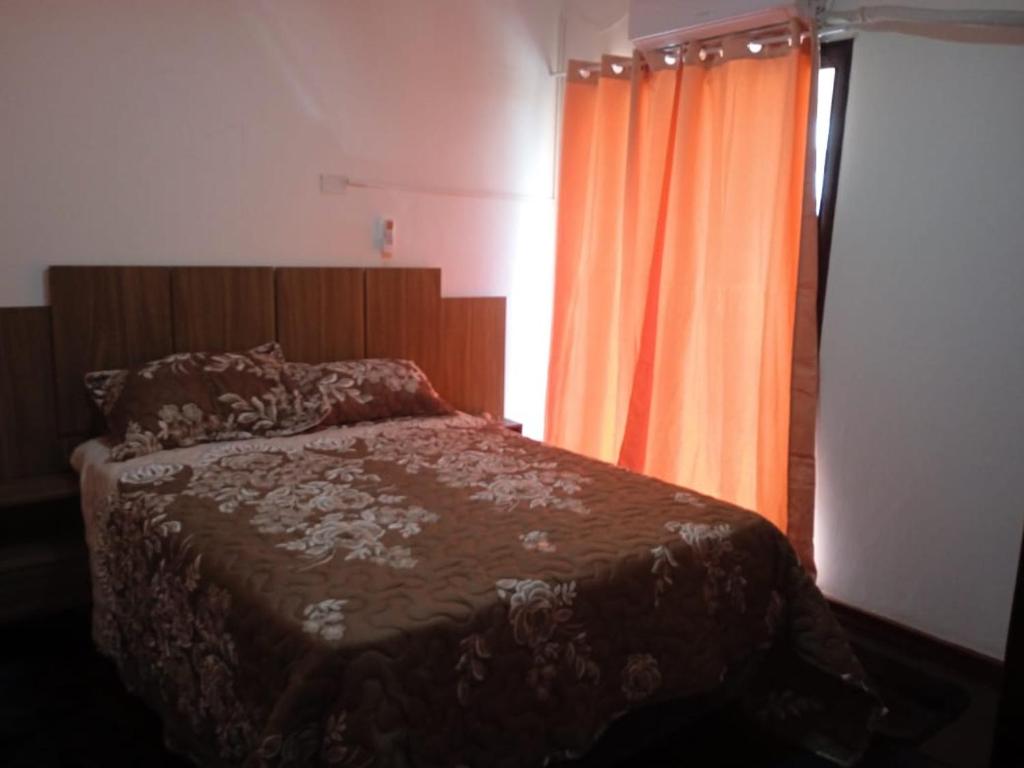 - une chambre avec un lit et un rideau orange dans l'établissement EDIFICIO PROGRESO, à Ciudad del Este
