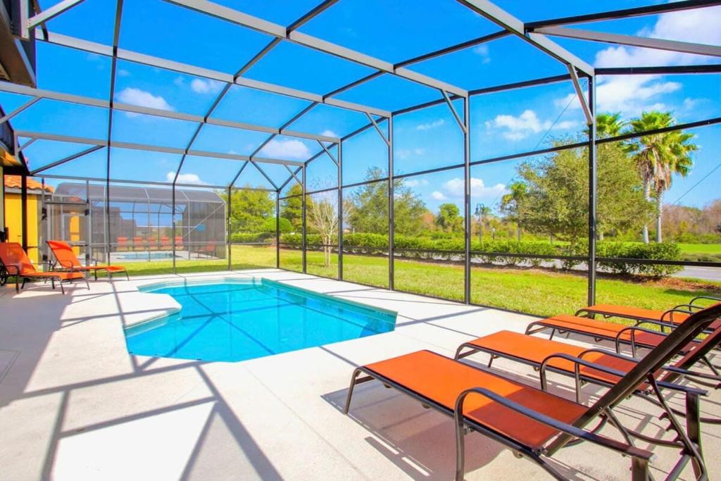 einen Pool in einem Glashaus mit Stühlen in der Unterkunft 4BR Home - Private Pool and BBQ - Near Disney! in Davenport