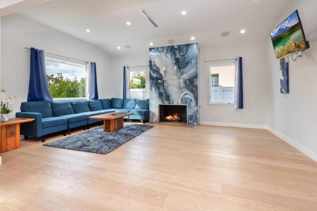 a living room with a blue couch and a fireplace at Prime Location, Stylish Space: 3BR Home with BBQ in Los Angeles