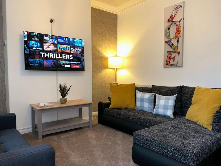 ein Wohnzimmer mit einem Sofa und einem TV in der Unterkunft Homely 3 Bed House Halifax in Exley