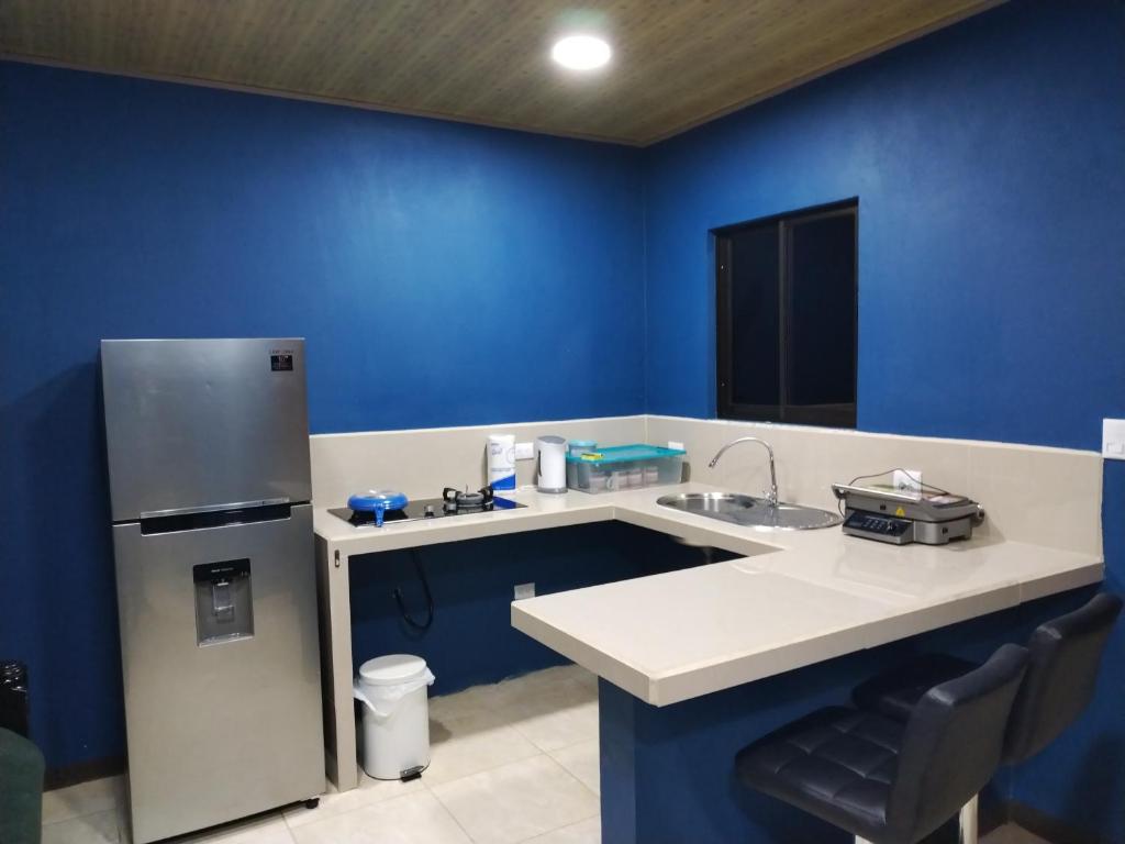 a blue kitchen with a sink and a refrigerator at Mini casa, Vara Blanca in Heredia