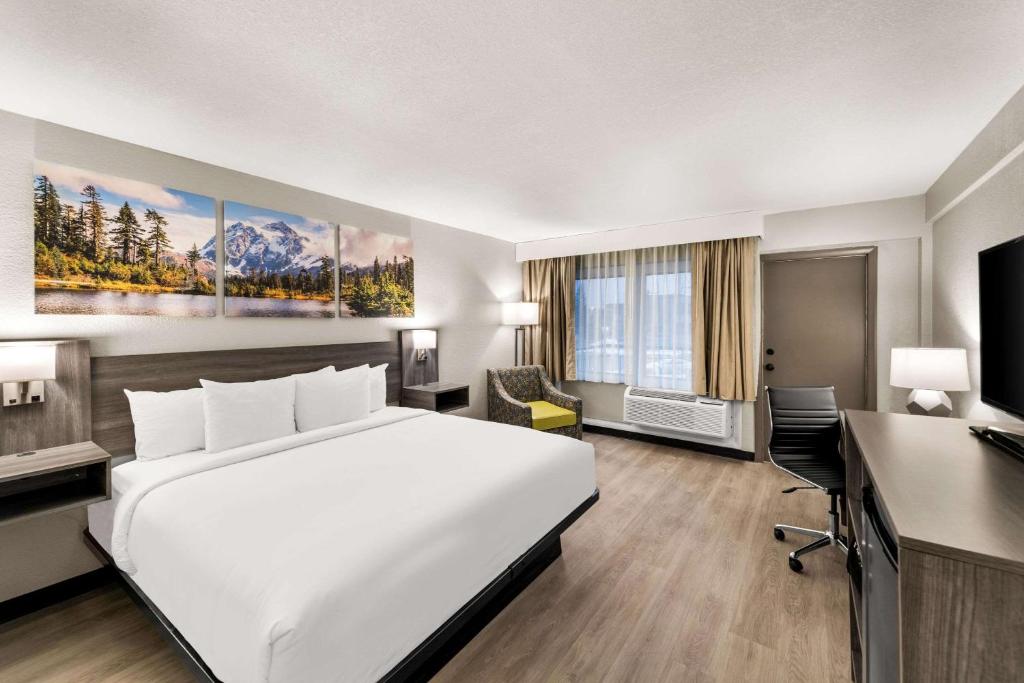 ein Hotelzimmer mit einem großen Bett und einem Schreibtisch in der Unterkunft Clarion Pointe Rhinelander Downtown in Rhinelander
