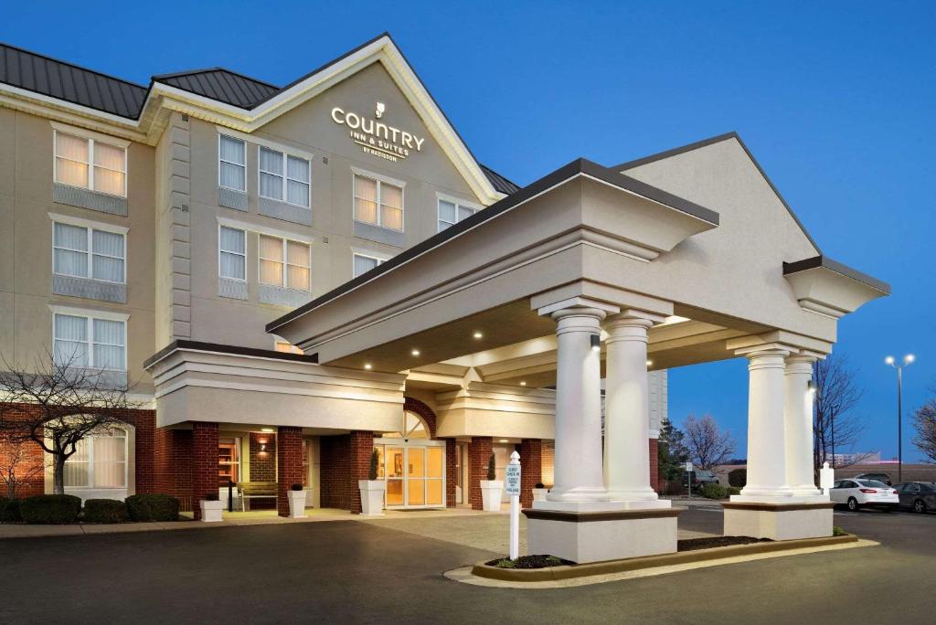 Country Inn & Suites by Radisson, Evansville, IN في إيفانسفيل: فندق فيه عماره فيه اعمده في مواقف السيارات