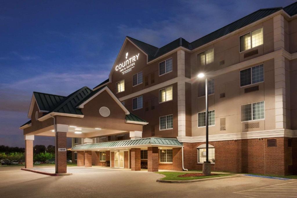 an exterior view of a hotel at night at Country Inn & Suites by Radisson, DFW Airport South, TX in Irving