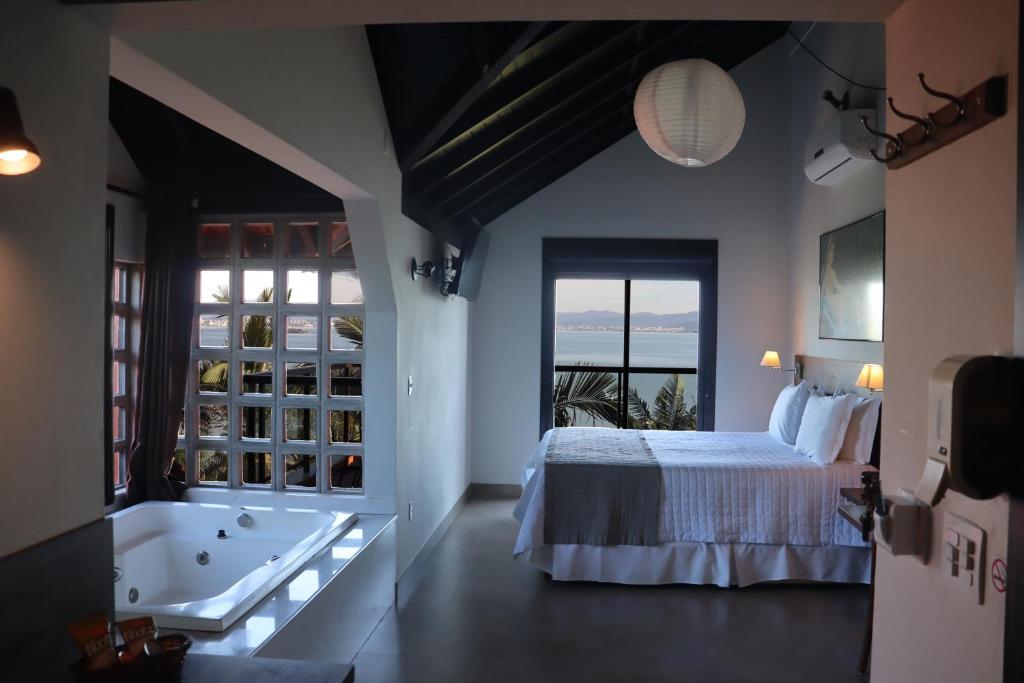 a bedroom with a bed and a tub and a window at Refúgio do Cacupé in Florianópolis