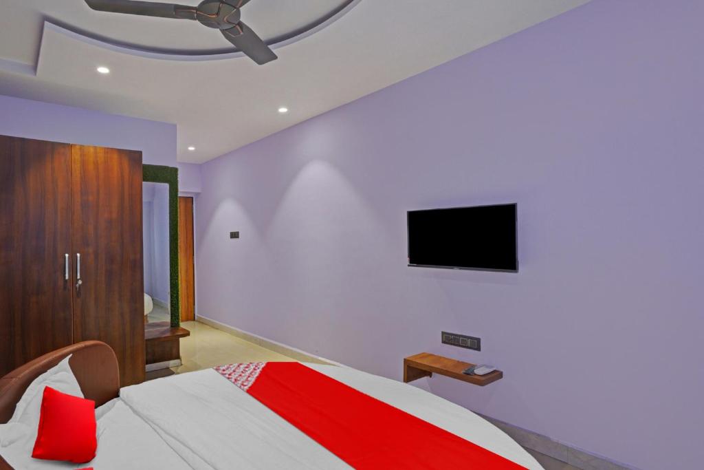 a bedroom with a bed and a tv on the wall at Flagship Hotel Happy Stay in Surat