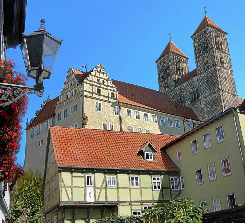 ein großes Gebäude mit einem Uhrturm und einer Kirche in der Unterkunft Hotel Domschatz in Quedlinburg