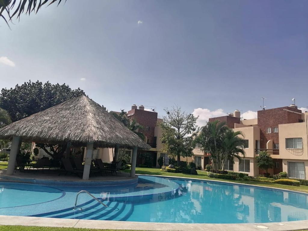 una gran piscina con sombrilla de paja y edificios en Casa en Cuernavaca, 