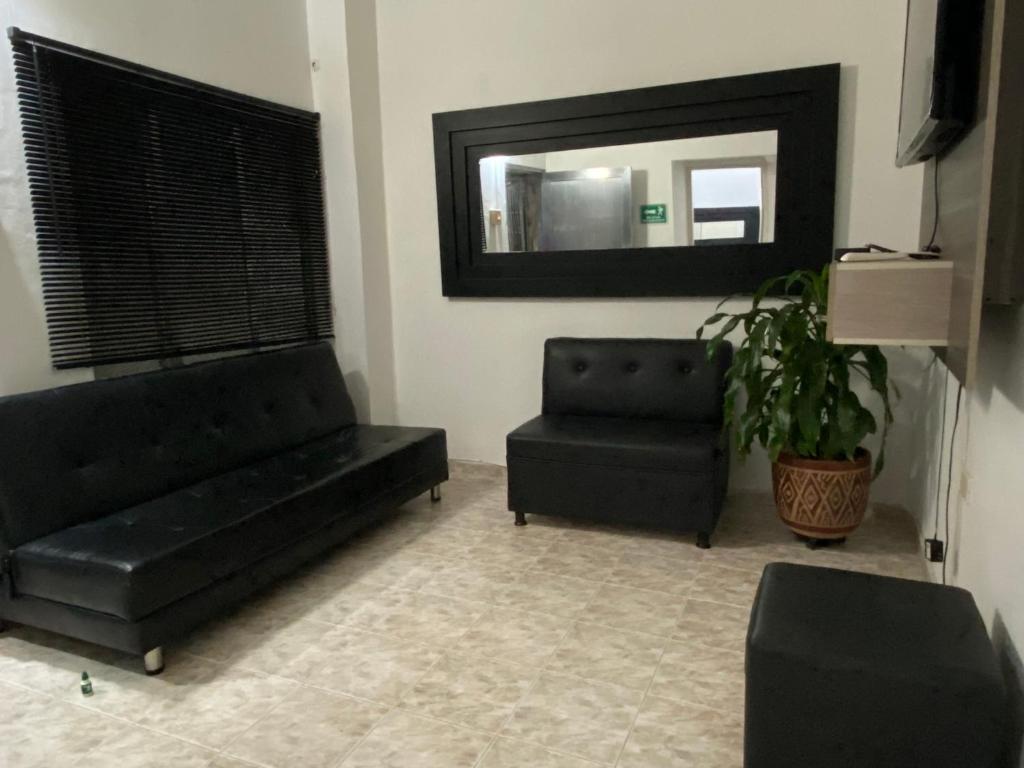 a living room with a black couch and a mirror at Apartamento central primer piso in Apartadó