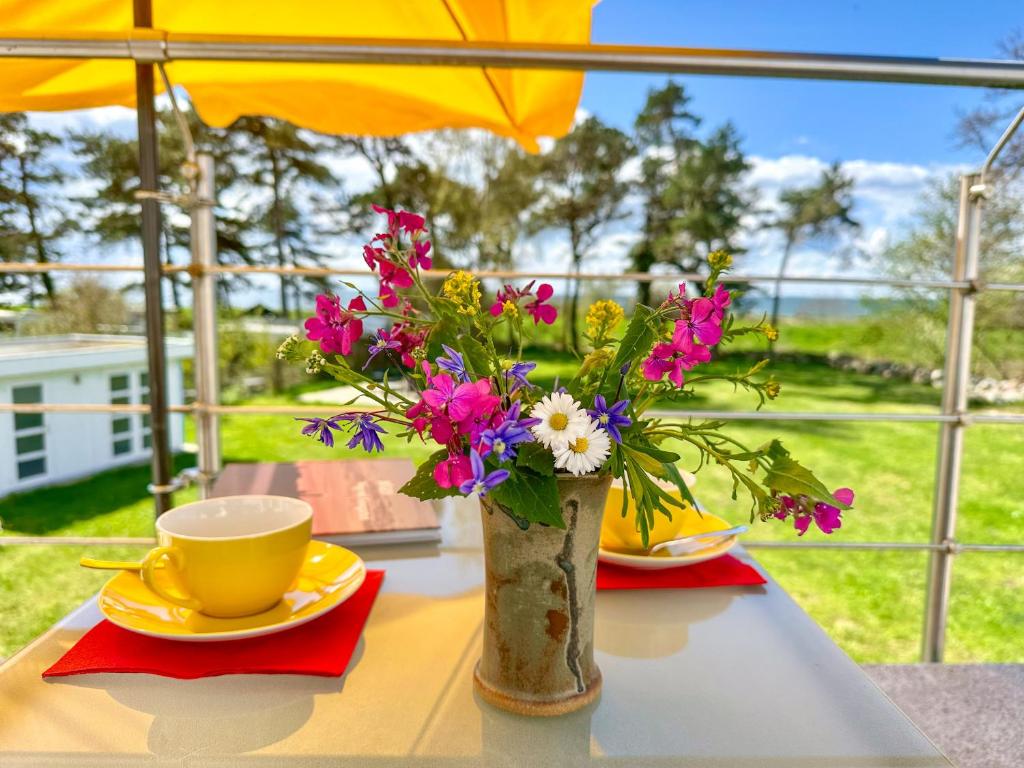 Villa "Windflüchter" في ثيسو: طاولة مع إناء من الزهور وكوب