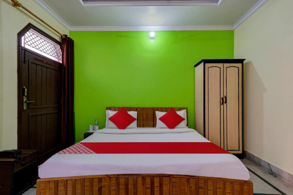 a bedroom with a bed with a green wall at Super OYO Flagship Rudraksh Hotel in Rāmnagar