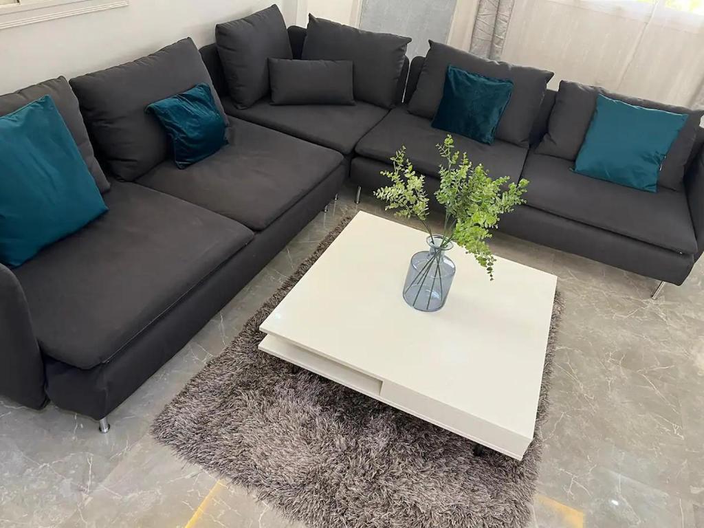 sala de estar con sofá negro y almohadas azules en American House en Accra