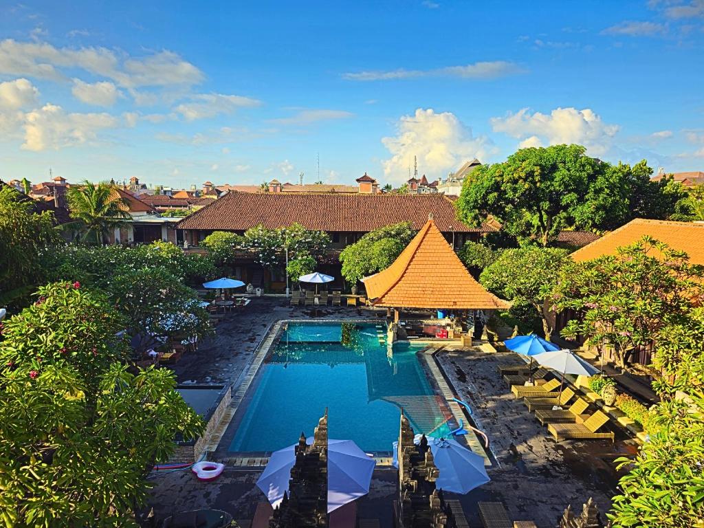 een uitzicht over het zwembad van het resort met stoelen en parasols bij Satriya Cottages in Kuta